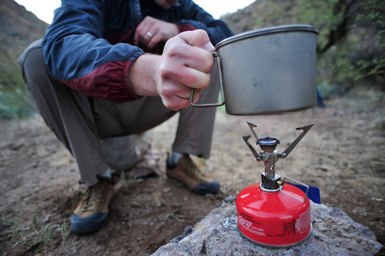 Woman and man backpackers prepare dinner with a camp stove at camp close to Charleboise Springs in La Barge Canyon on the Dutchmans Trail in the Superstition Wilderness Area, Tonto National Forest near Phoenix, Arizona November 2011. 