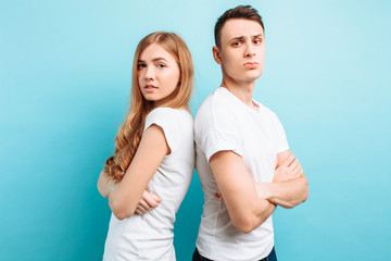 loving couple, man and woman, dressed in white T-shirts, back-to-back and smiling, against a blue background