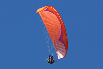 Tandem paraglider flying red wing