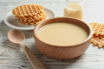 Bowl with condensed milk served on table, closeup. Dairy products