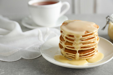 Plate with pancakes and condensed milk served on table, space for text. Dairy product