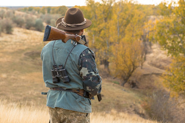 Hunter with a hat and a gun in search of prey in the steppe	