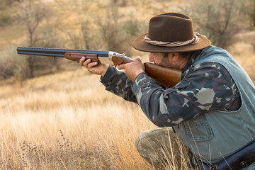 Hunter with a hat and a gun in search of prey in the steppe	