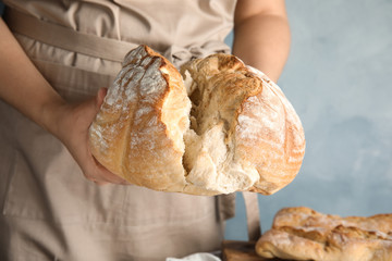 Man holding whole wheat bread on color background, closeup