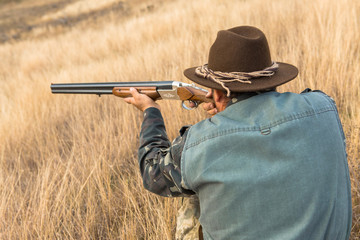 Hunter with a hat and a gun in search of prey in the steppe	