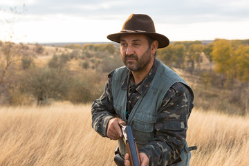 Hunter with a hat and a gun in search of prey in the steppe	
