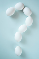 Question mark folded from white eggs on bright background. Conceptual photo. Easter celebrate symbol.