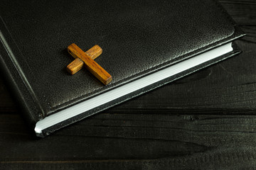 wooden cross on a book on a black wooden table