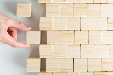 Woman's hands finishing wooden cube pattern. Placing missing piece