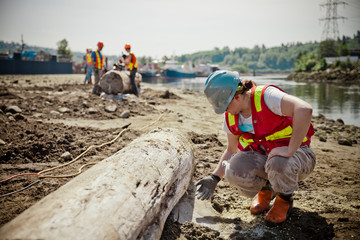 A woman checks to see if the concrete is dry on a job site focused on estuary restoration.