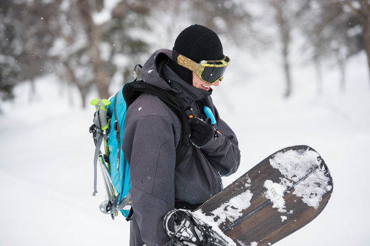 A snowboarder talking over his radio in the backcountry