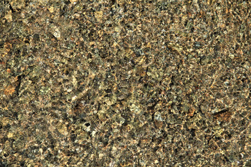 Mosaic texture with the golden shade (tint) in the sunrays. The bottom of the lake with pebbles under the clear water close-up, background