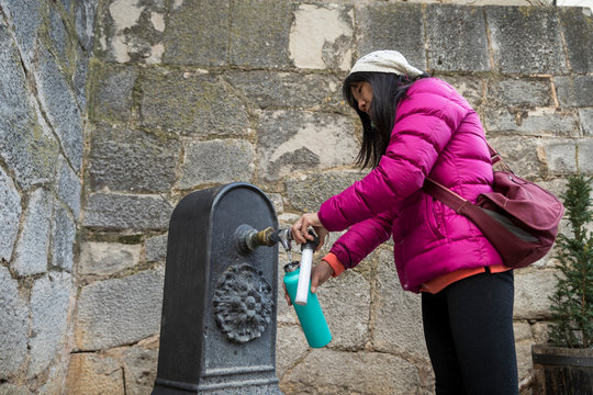 Woman filling water bottle from fountain