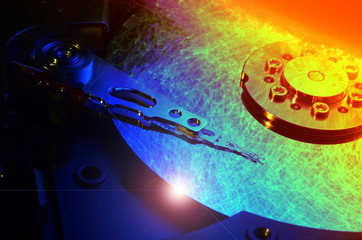 Close up on opened computer hard disk drive with colored optic fiber.