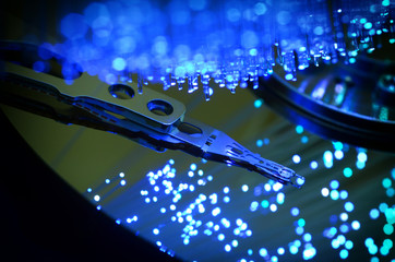 Close up on opened computer hard disk drive with colored optic fiber.