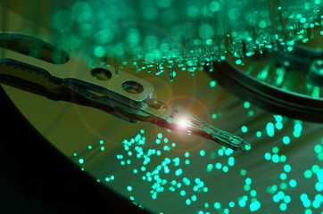 Close up on opened computer hard disk drive with colored optic fiber.