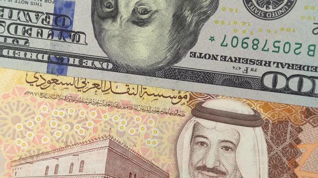 Saudi Arabia riyal against US dollar bill rotating. Saudi Arabia and USA trade. 4K stock video footage