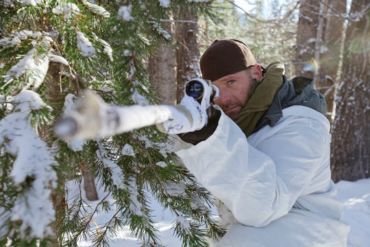 Portrait of a hunter aiming his rifel while hunter in winter conditions.