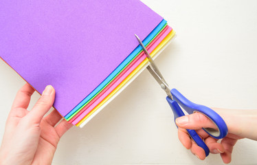 Cutting through few colorful sheets of eva foam with scissors
