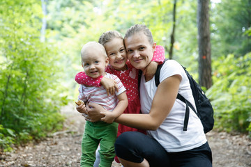 Devoted mother hugging her son and daughter, enjoying the outdoor.