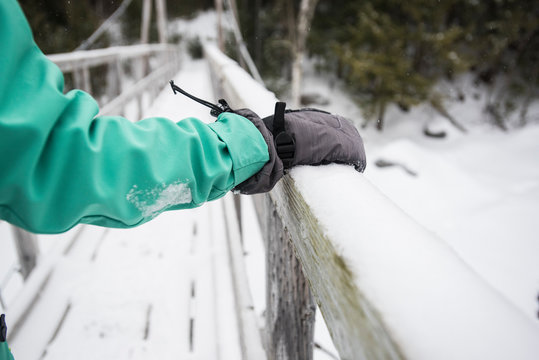 Person hiking across?footbridge?in winter