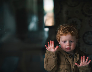 Toddler boy looking through window