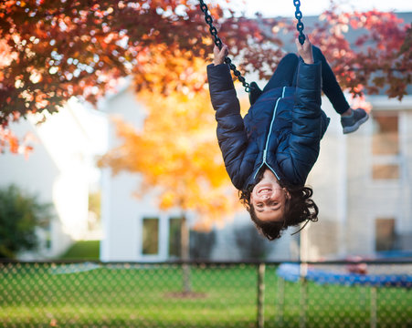Girl swinging upside down in backyard with happy expression