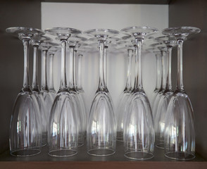 Selective focus view of an upside down row set of champagne and cocktail clean empty glasses waiting to be used in the cupboard of a restaurant of Spain
