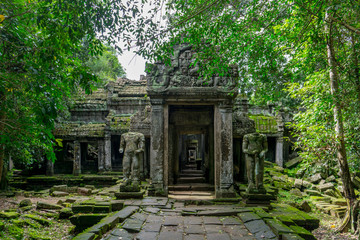 Obraz premium Statues stand guard before the entrance to a temple at the Angkor archeological park