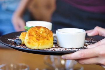 Cottage cheese pancakes with blueberry and mint for Breakfast or lunch. Jam and sour cream. The girl's hands holding the finished dish.