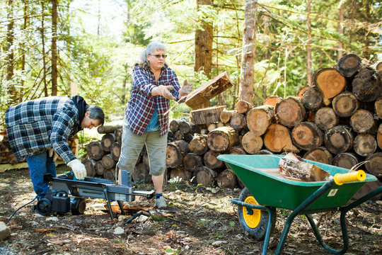 Couple splitting firewood with man using wood splitter machine