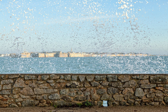 Water splashing after wave crashing on stone wall on coastline