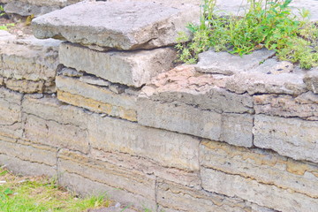 Image of an old stone wall, overgrown with grass and crumbling masonry