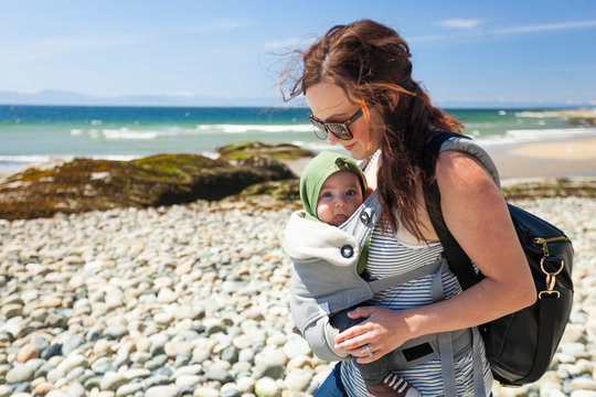 Mother With Baby Son In Carrier At Beach