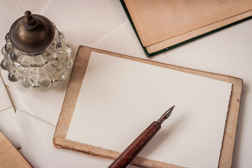 Old wooden pen with feather and inkwell, flat lay. Vintage background with copy space. Memory and...