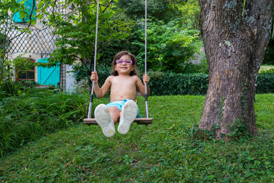 Front view of girl swinging in garden in summer, Genolier, Switzerland