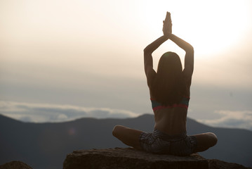 Woman sitting on rock while practicing yoga