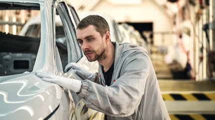 An employee of the car body painting shop checks the quality