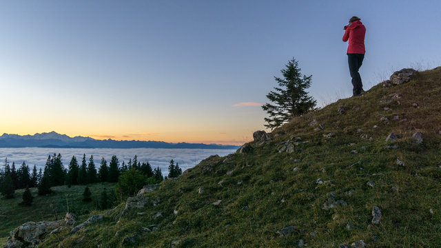 Person photographing sunrise from hill near Geneva Lake, Gingins, Vaud, Switzerland