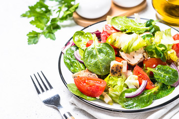 Green salad with chicken and vegetables on white.