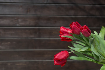 Bouquet of  red tulips  on a dark brown wooden background. Festive concept. Space for copy space.
