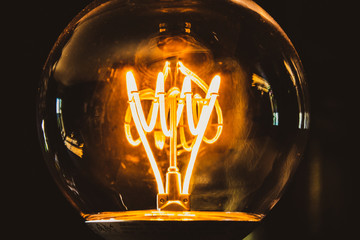 Classic retro incandescent edison light bulb: close up of the glowing filament