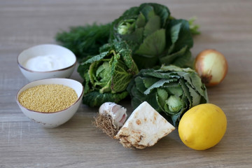 Celery, cabbage, kale, onion, lemon, garlic, millet and yoghurt on a wooden table. Ingredients for a creamy soup.