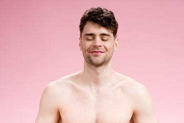 Fototapeta premium handsome, smiling brunette man with closed eyes on pink