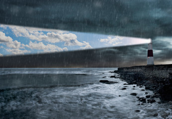 Lighthouse emitting beam of blue sky and clouds in a storm