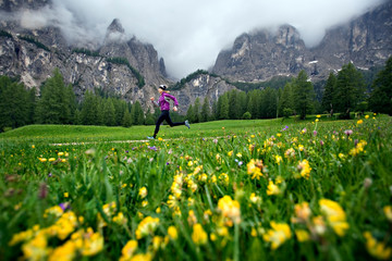 Woman running on flower lined mountain trail