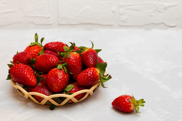 Fresh and juicy strawberries in a basket on neutral background with copy space