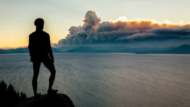 A mountain biker stops on the Flume Trail to watch smoke from a wildfire.