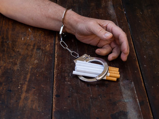 A man handcuffed to a handful of cigarettes. Tobacco addiction concept
