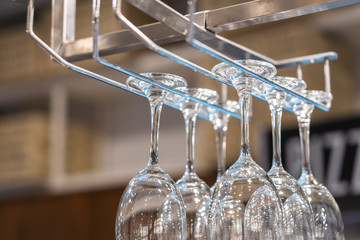empty wine glasses hanging on shelf of bar rack in urban restaurant, pub beverage corner with copy space